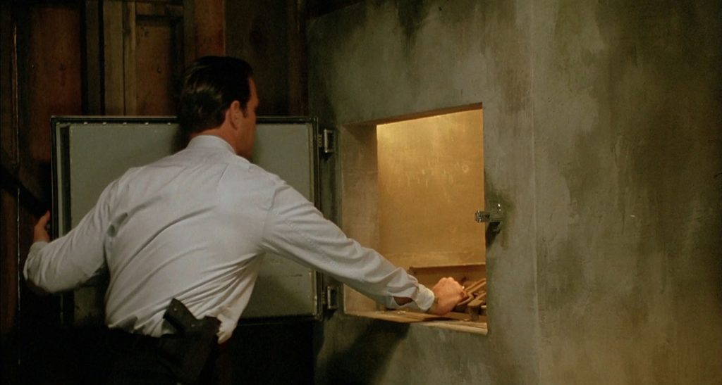 A man with a gun standing by a morgue freezer door