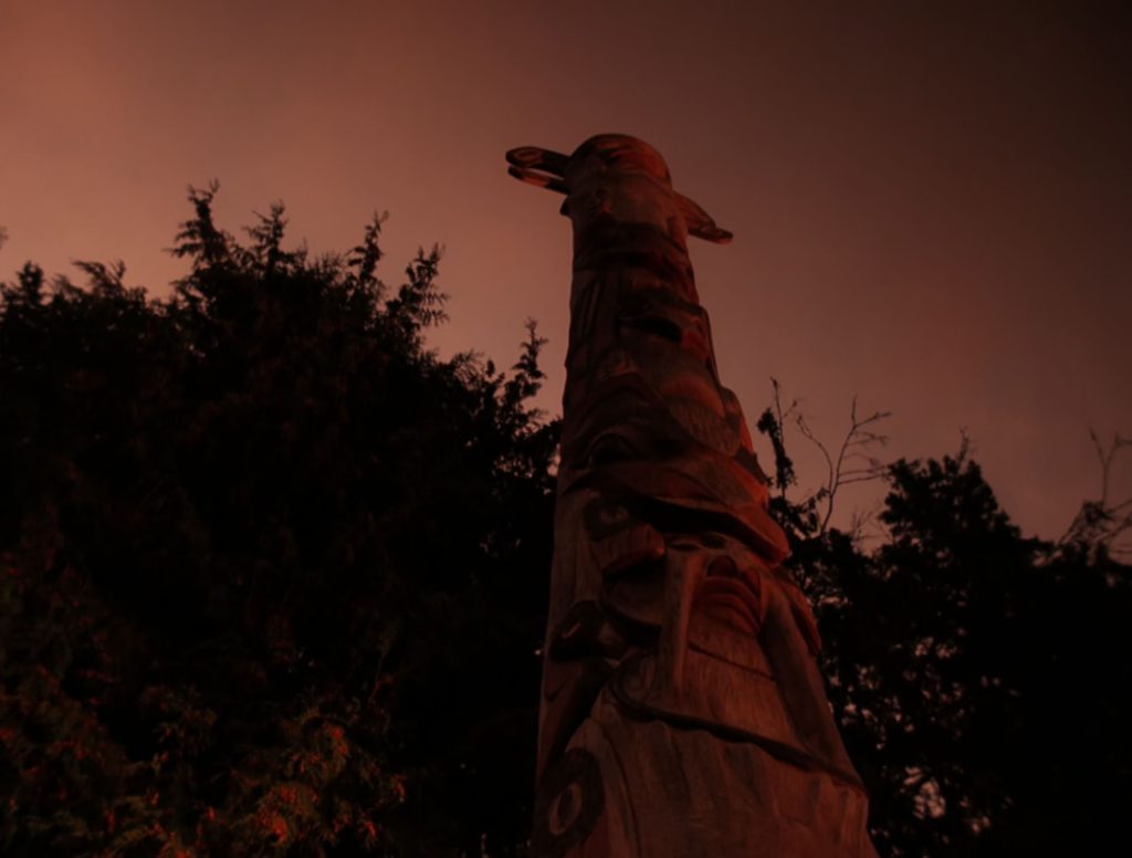 Tall wooden carved story pole at sunset