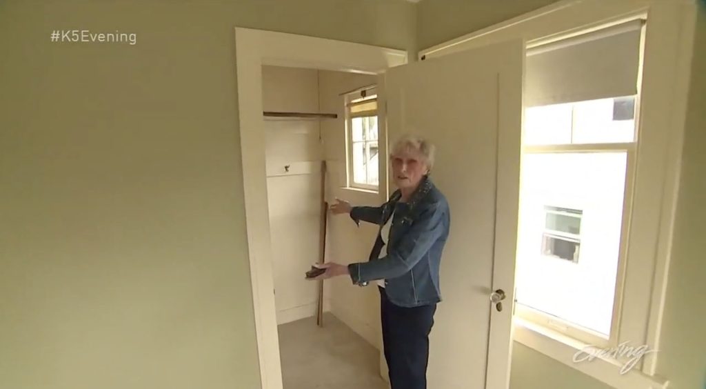 Person in a bedroom standing by an open closet door