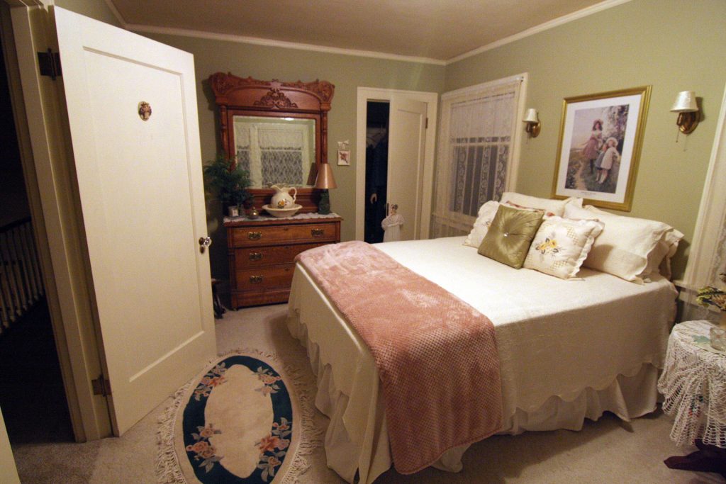 Bedroom with a door, bed, dresser and windows