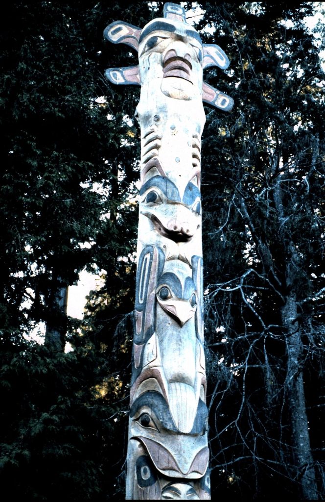 Carved story pole against trees
