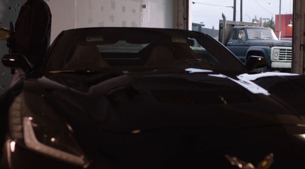 Guy leaning on a black Corvette