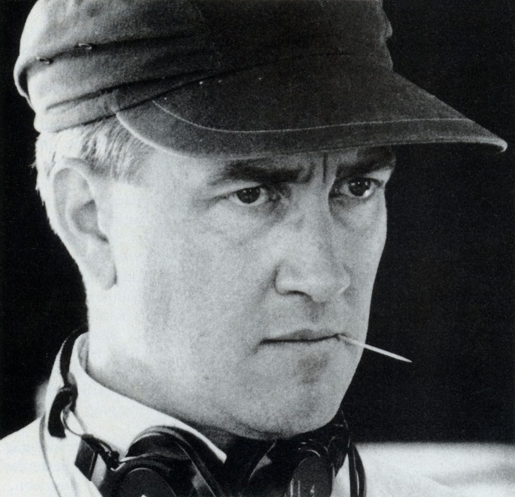 Black and white image of David Lynch wearing a hat and chewing on a tooth pick