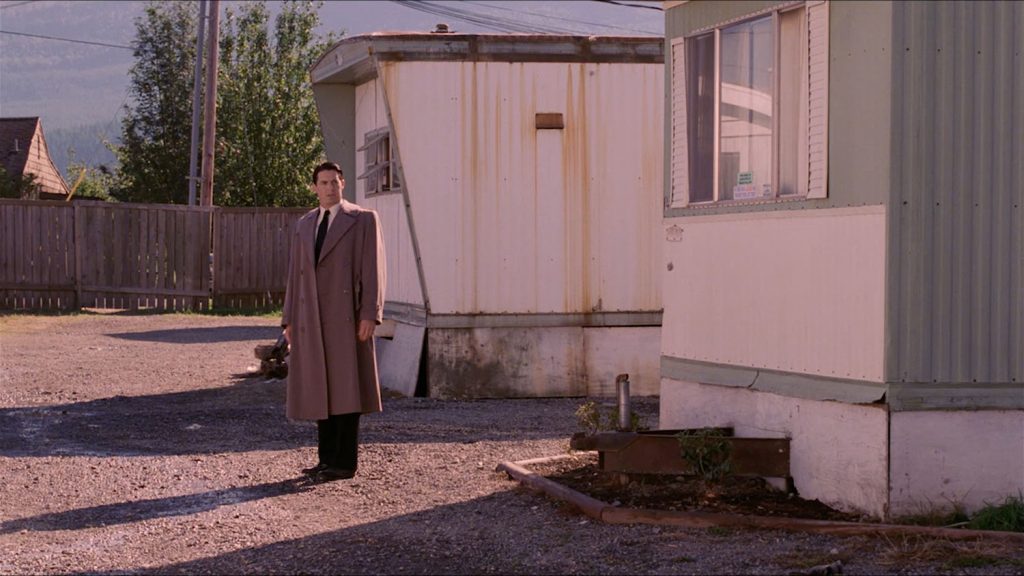 Agent Cooper standing in an overcoat by trailers