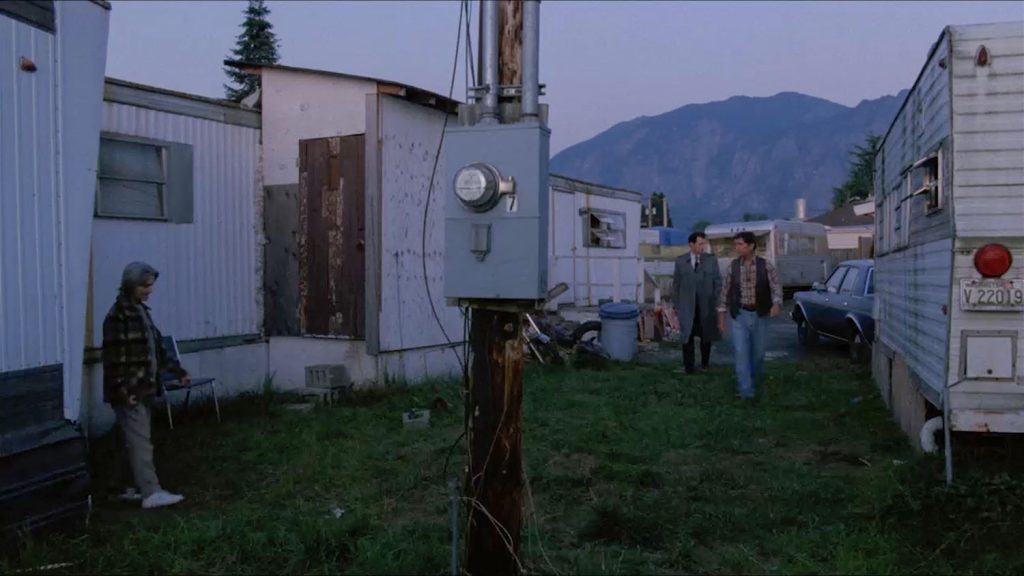 Three people walking in a trailer park at dusk