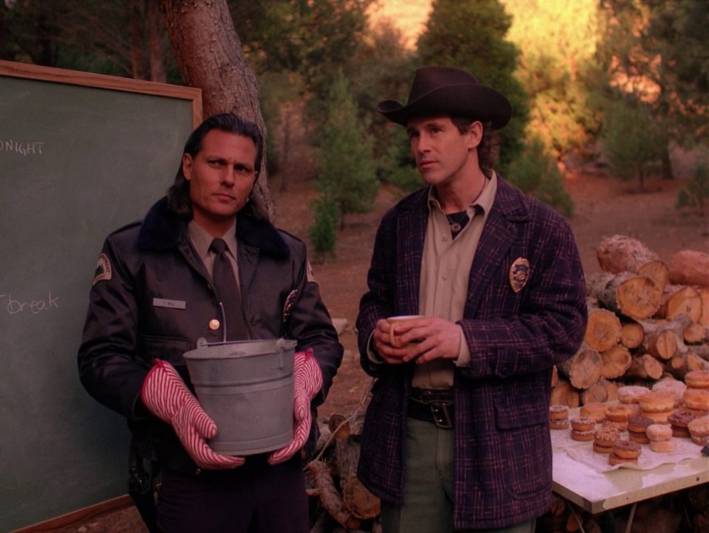 Deputy Hawk holding a bucket wearing oven mitts and standing next to Sheriff Harry S. Truman