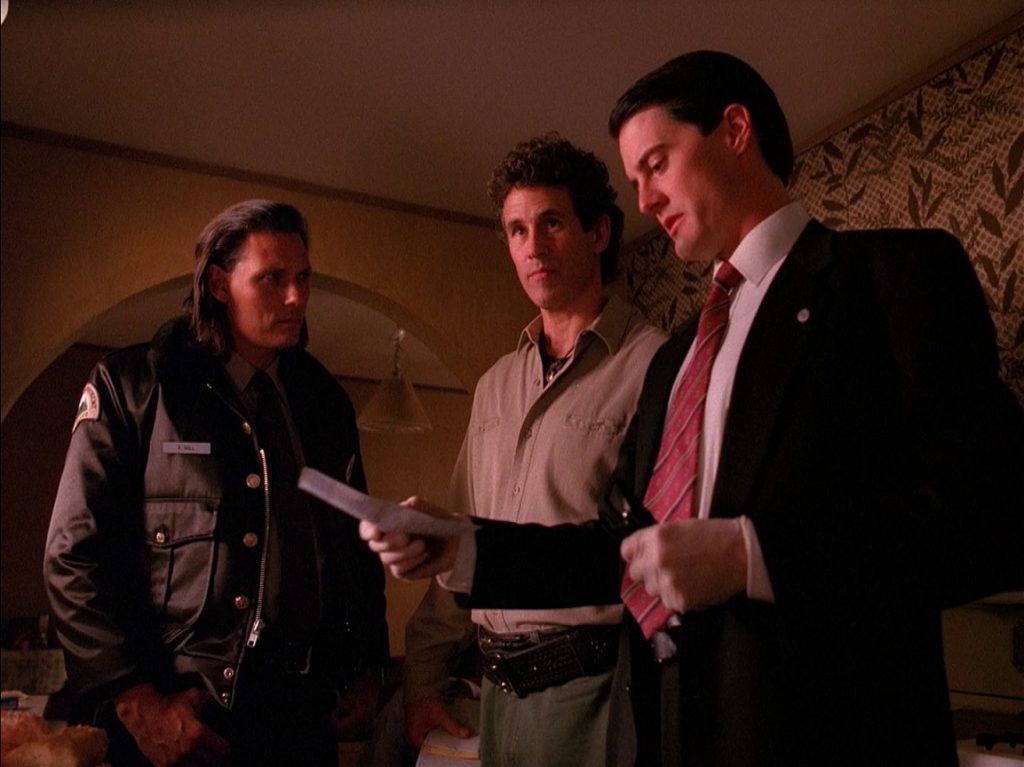 Deputy Hawk, Sheriff Truman and Agent Cooper discuss in Jacques Renault's apartment