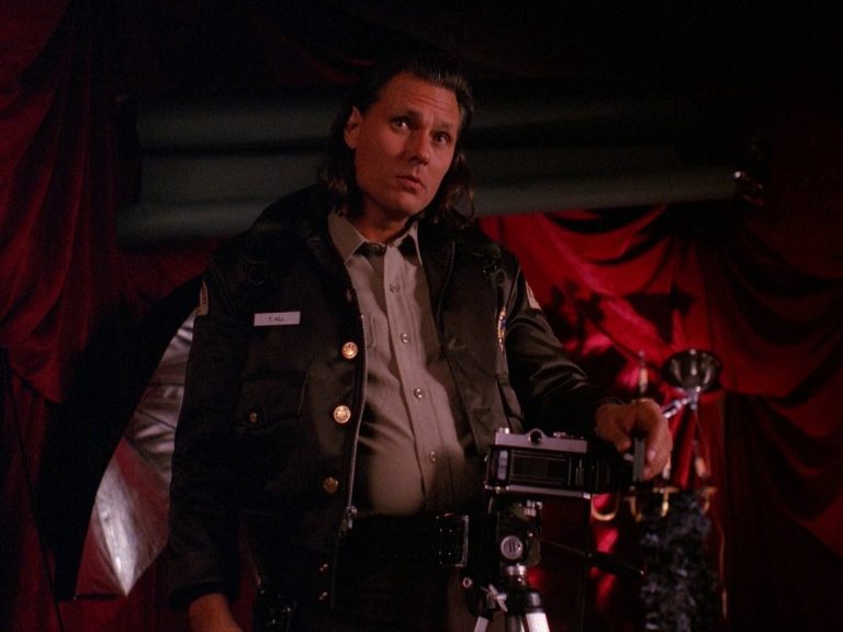 Deputy Hawk standing next to a camera in a cabin