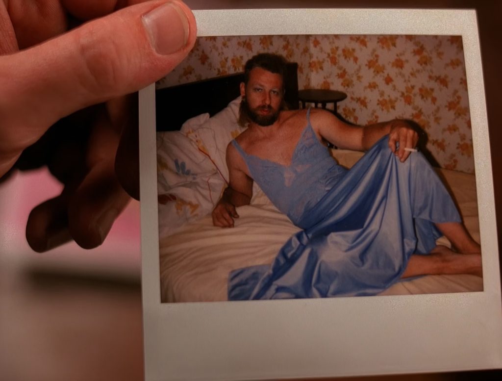 Polaroid image of a gentleman wearing blue lingerie and laying on a bed