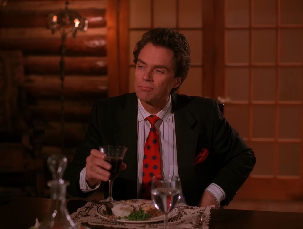 Ben Horne sitting at a table with dinner and holding a wine glass
