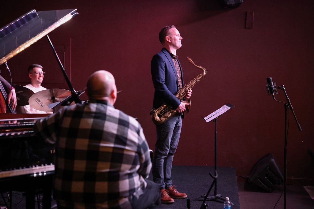 Andrew Glynn with a saxophone standing on stage
