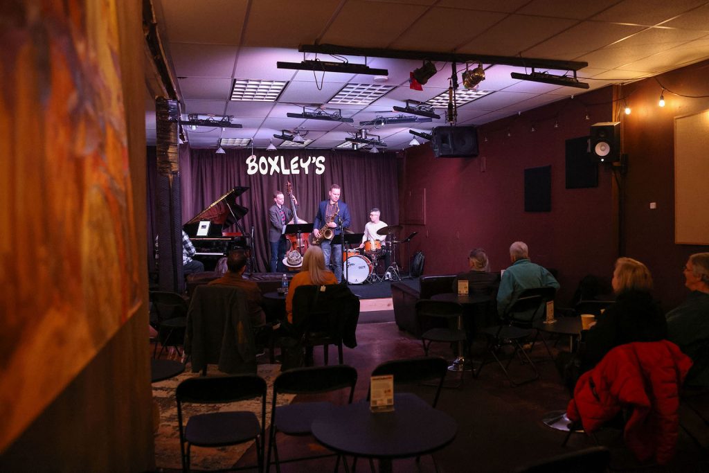 Inside of Boxley's Jazz Club with quartet playing on stage while people watch