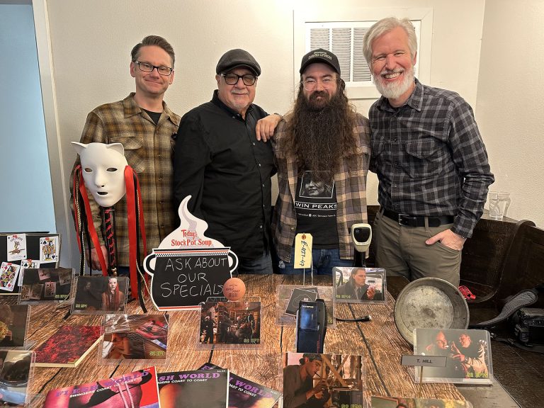 Four people standing behind a table of props