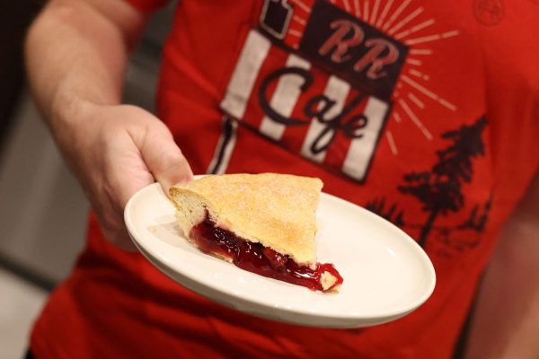 Person holding slice of cherry pie on a plate
