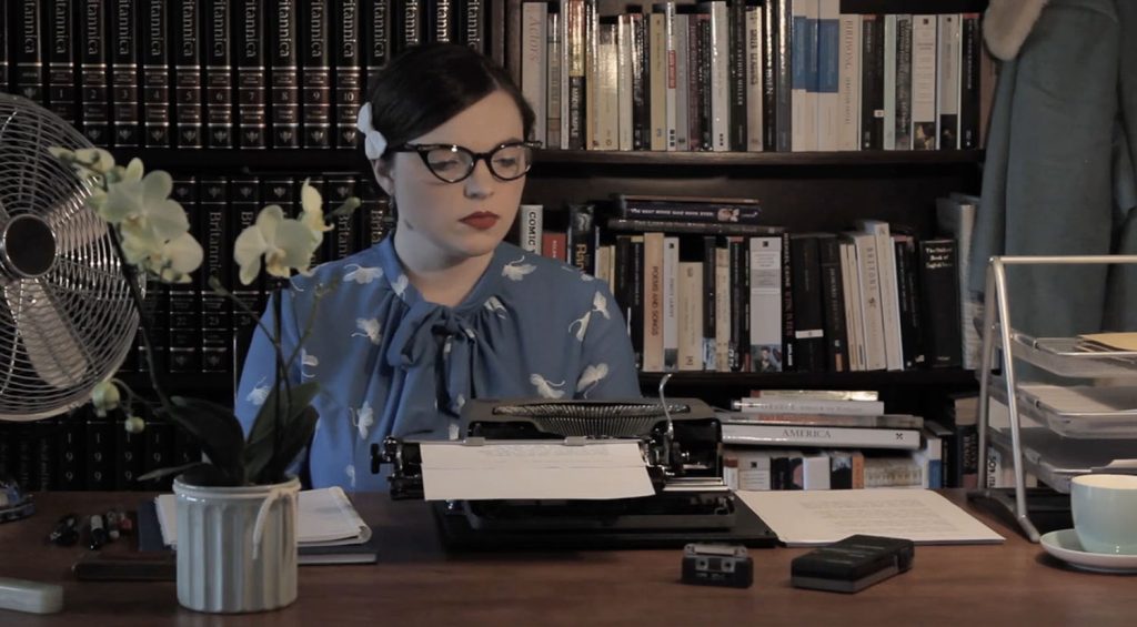 Diane (Naomi Shields) sitting at a desk with a typewriter