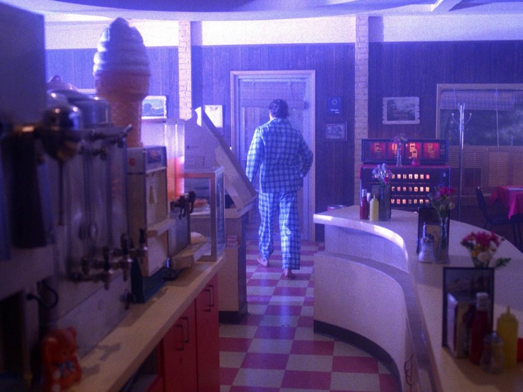 Hank Jennings in the Double R Diner answering the front door in his pajamas while lightning flashes