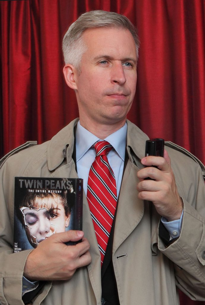 Steven dressed as a special agent holding The Twin Peaks: The Entire Mystery Blu-ray set