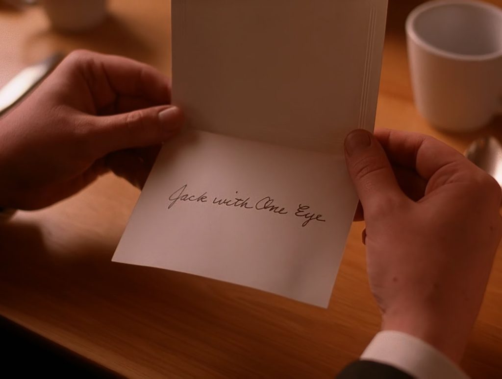 Cooper holding a note from Audrey that reads "Jack with One Eye"