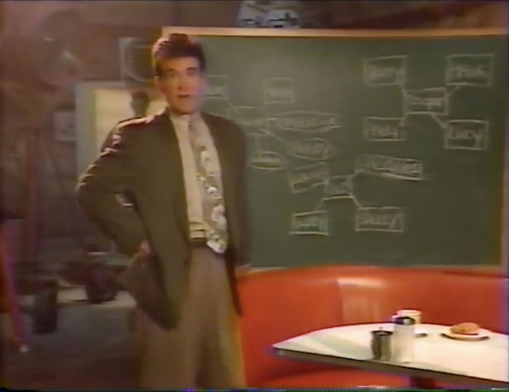 Alan Thicke next to a chalkboard