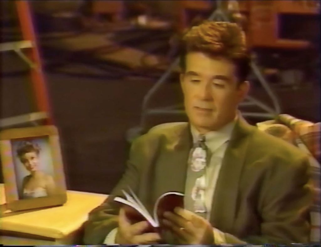 Alan Thicke sitting on a couch holding a diary