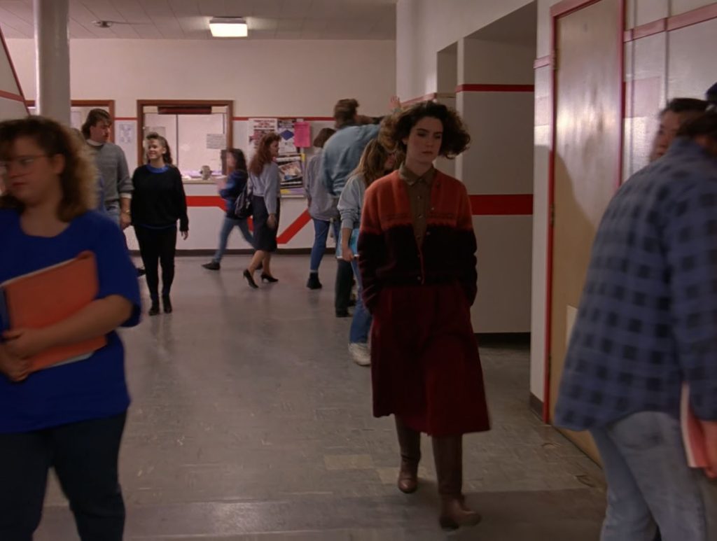 Donna Hayward walking down a school hallway