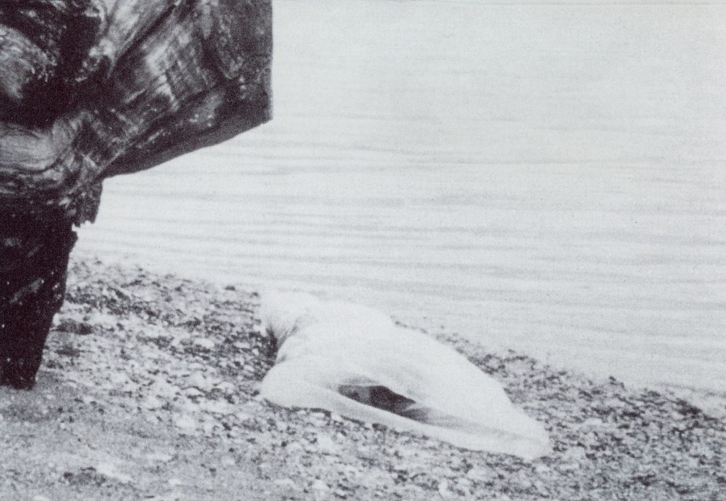 Black and white image of Laura Palmer's body wrapped in plastic by log