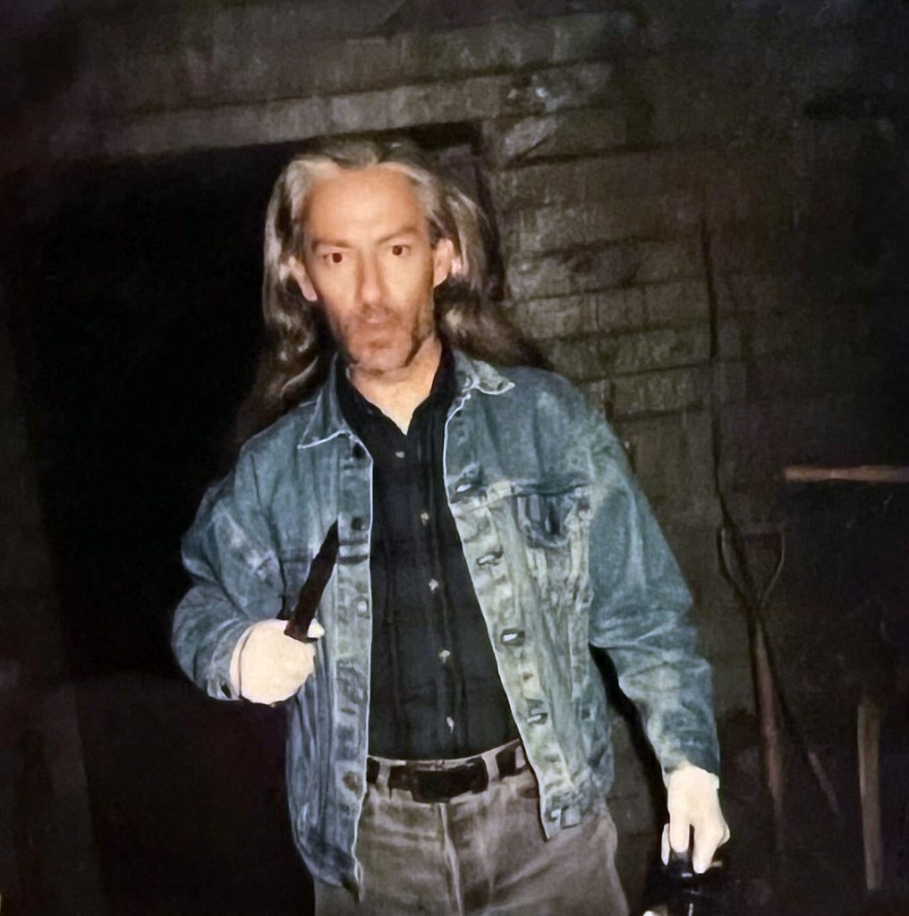 Behind the scenes photo of Killer BOB holding a knife in the train car