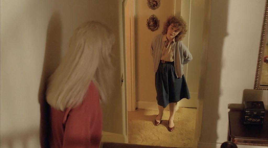 Sarah Palmer standing at the foot of the stairs as Laura Palmer looks back