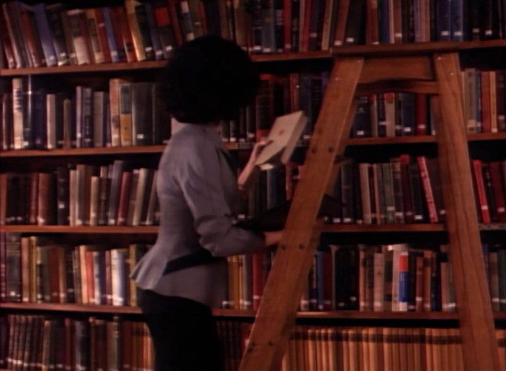 Audrey Horne climbing down a wooden ladder in the library