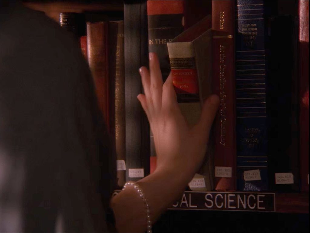 Audrey Horne selecting a book from the bookshelf