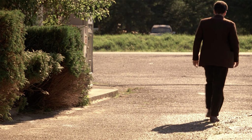 Leland Palmer walking by bushes and vending machines