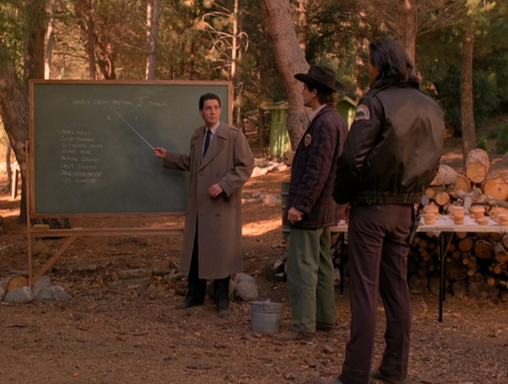 Cooper standing at the chalkboard in the woods