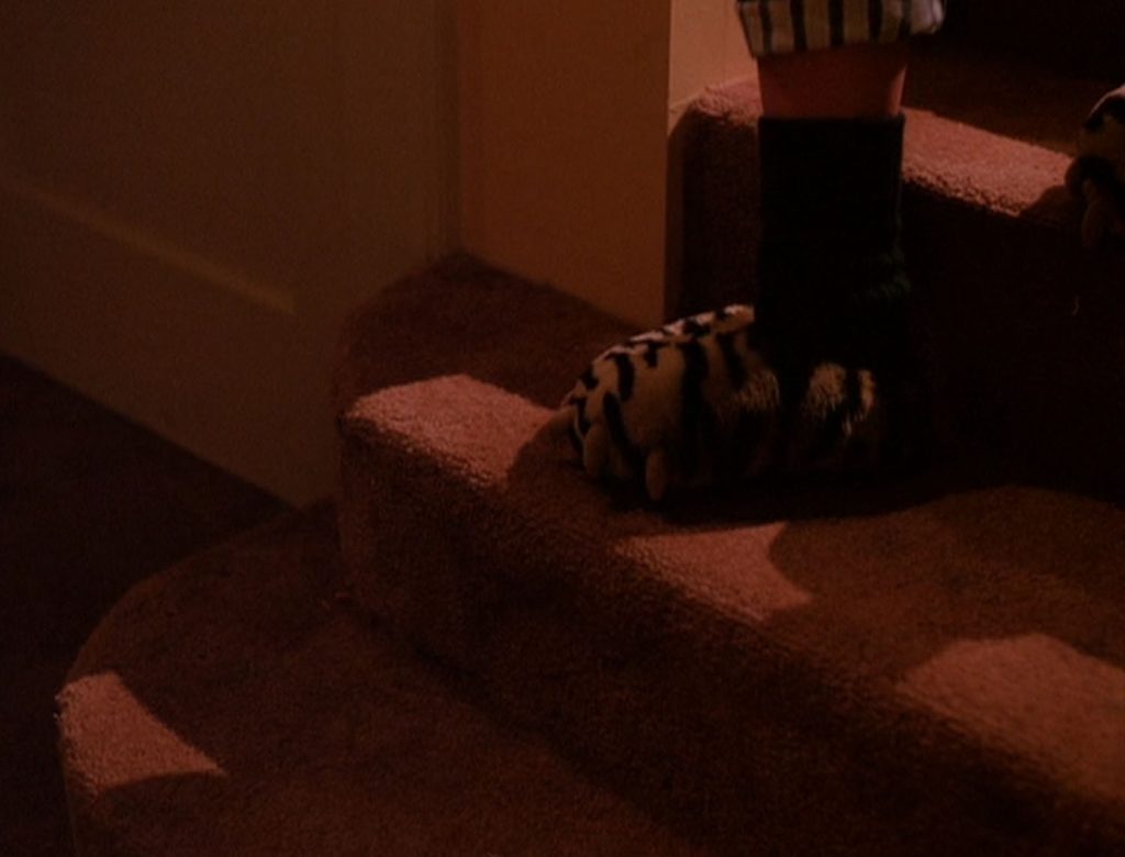 Maddy wearing monster slippers stepping down stairs