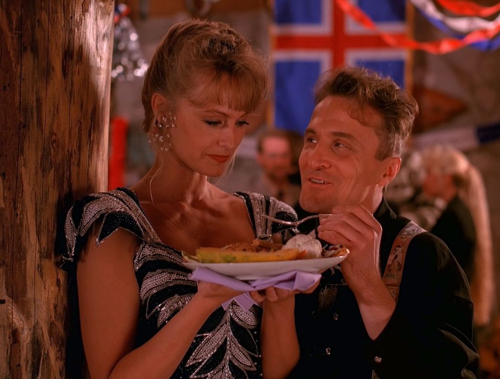 Heba holding a plate of food while Jerry Horne speaks with her at a party