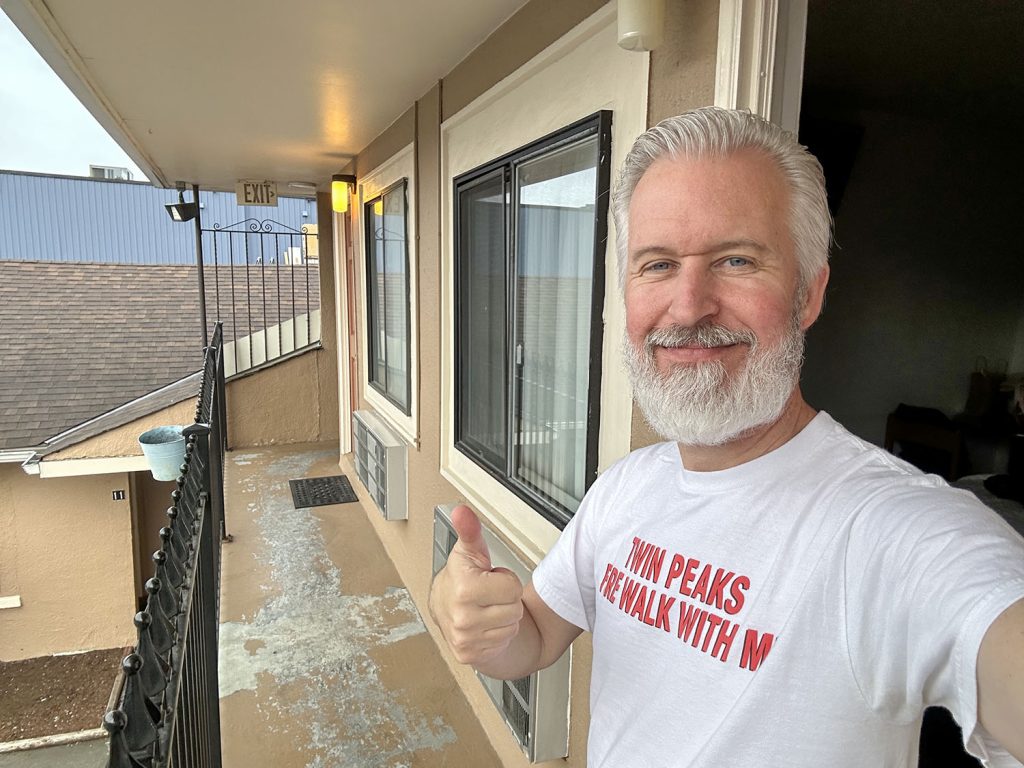 Steven standing on balcony holding a thumb up