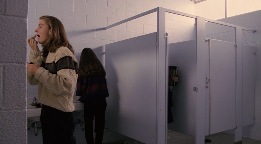 Laura Palmer entering a bathroom stall while two other students are in the bathroom