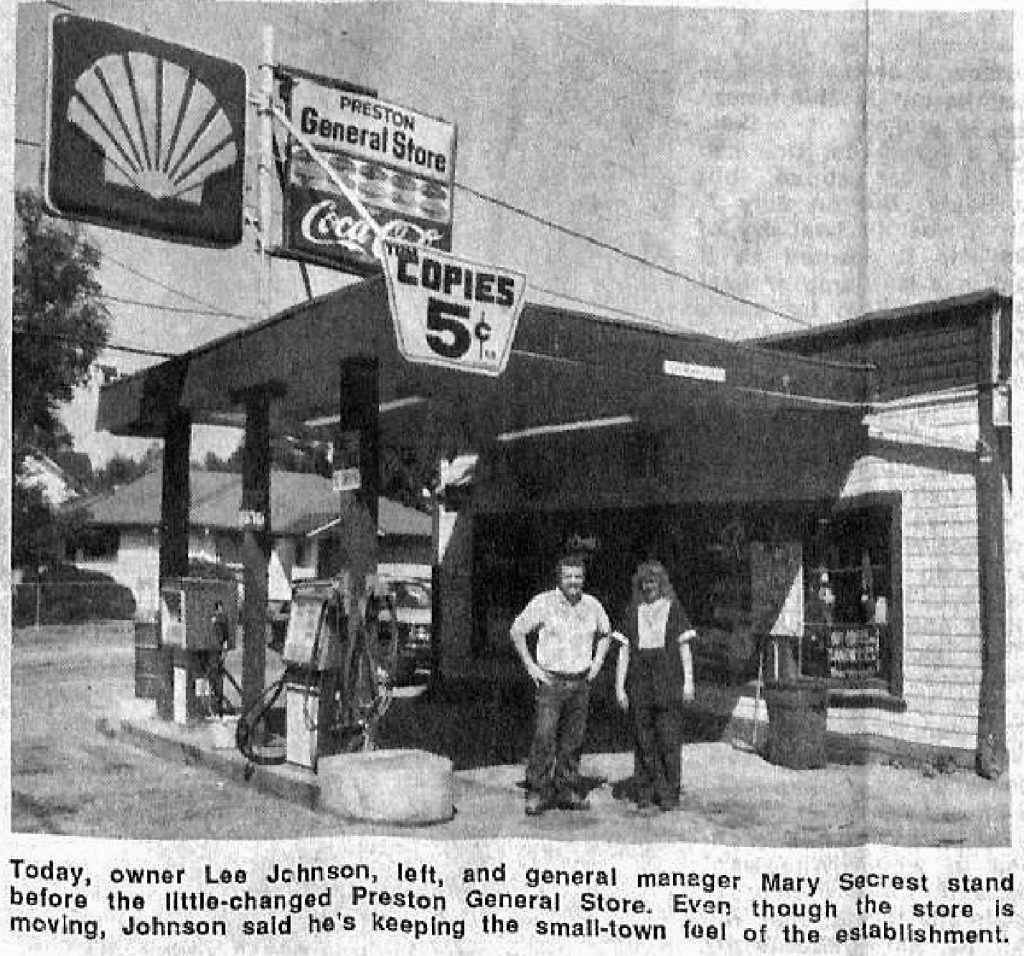 Black and White photo of a man and a woman standing outside a gas station named Preston General Store