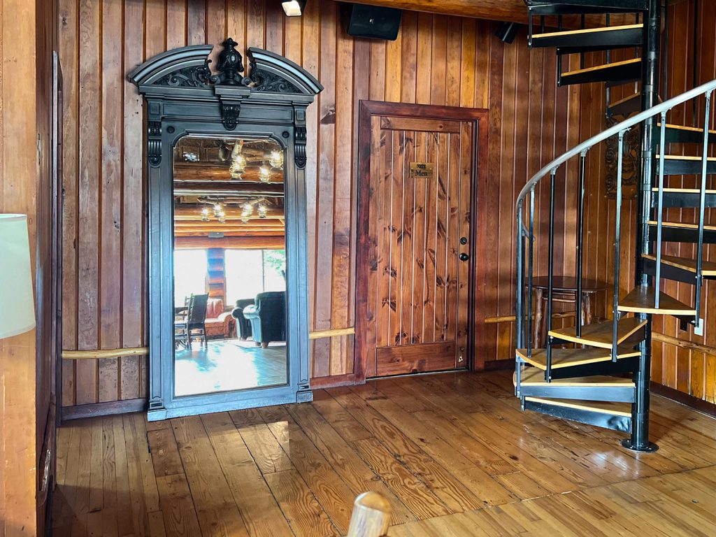 A giant mirror leaning against a wall in a room next to a spiral staircase