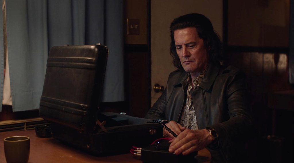 Mr. C at a small desk with a briefcase and recording device.