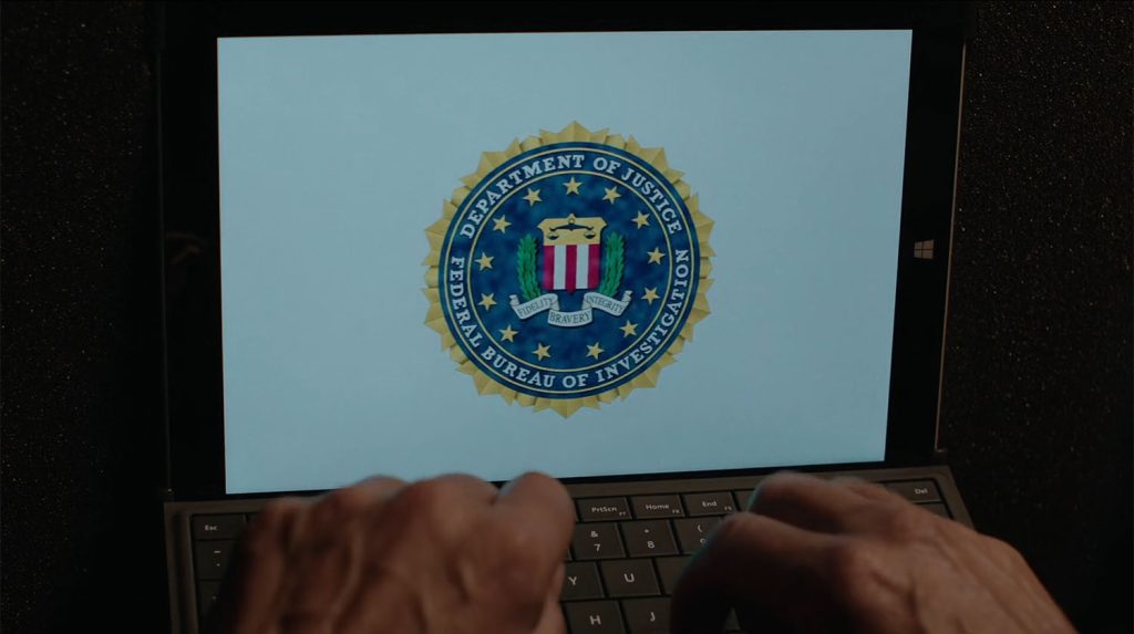 Hands on a keyboard with the FBI logo on a screen