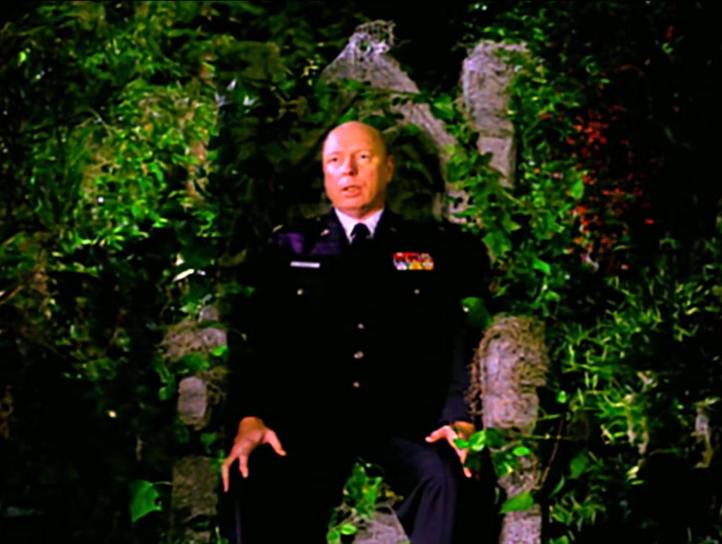 Major Briggs sitting on a stone throne in the woods