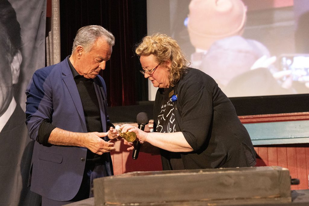 Beth Burrows adding oil to Ray Wise's hands