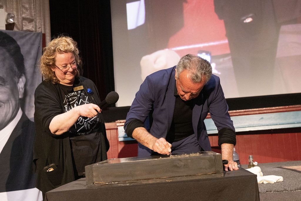 Ray Wise signing his name while Beth Burrows looks on