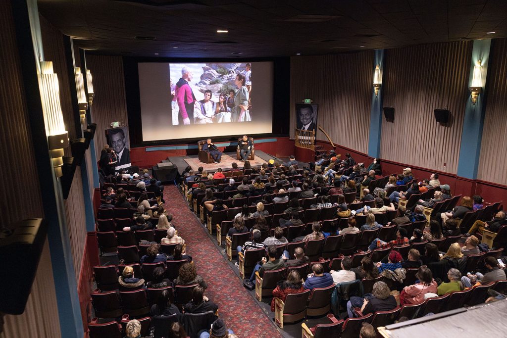 Theatre with audience watching Ray Wise and Mike McGraner speak