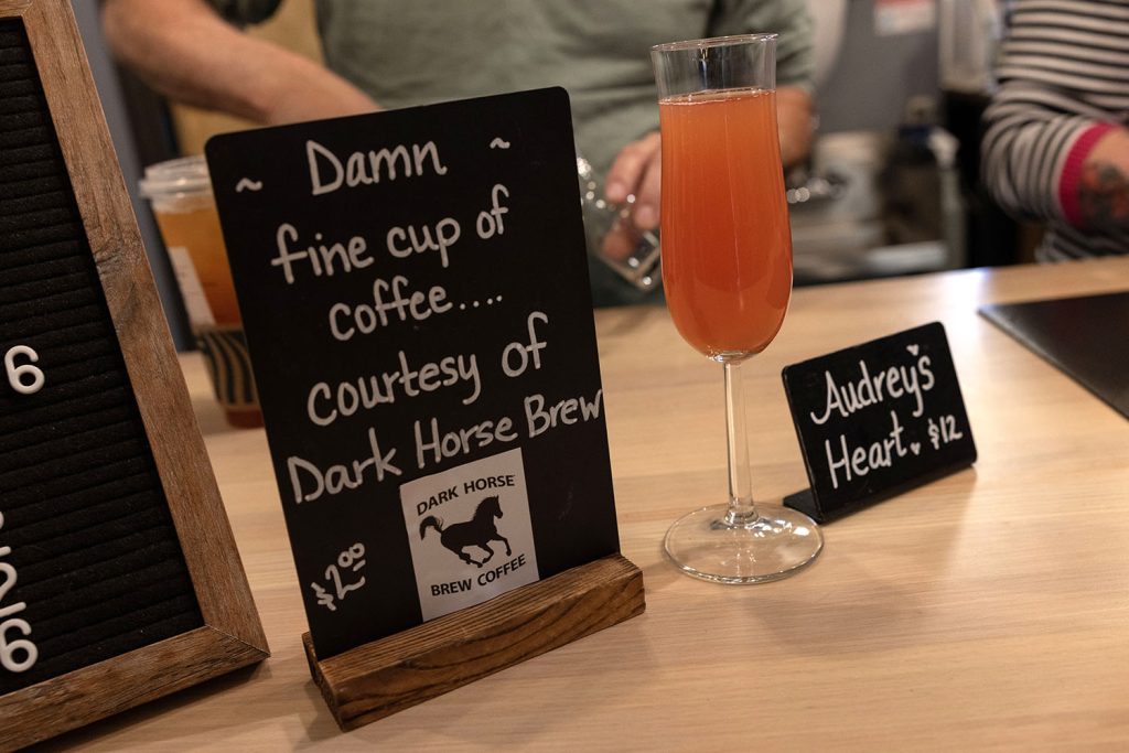 Display board with drink specials and a class with a coral-colored drink