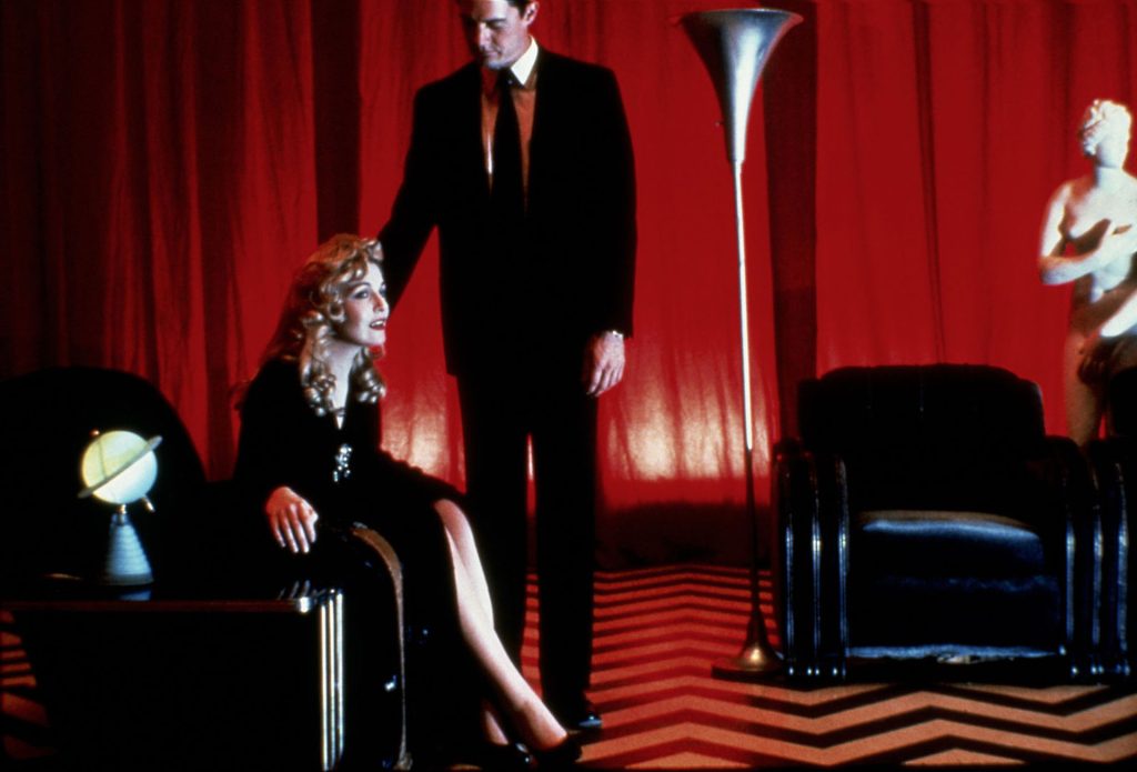 Laura Palmer sitting in a chair in The Red Room with Agent Cooper standing nearby