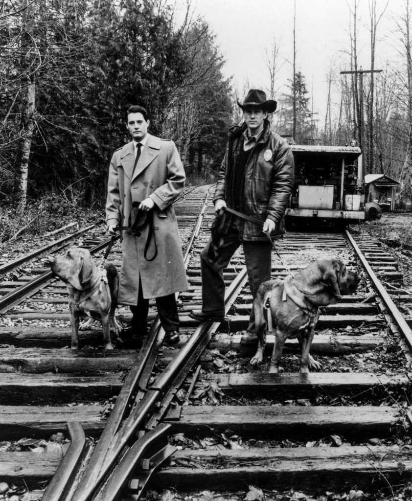 Black and White photo of Agent Cooper and Sheriff Truman on train tracks with dogs