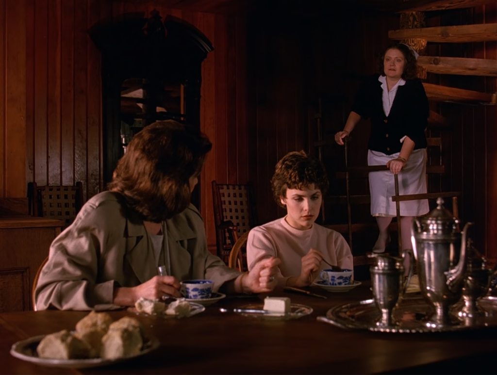 Sylvia and Audrey Horne at a dining room table with a Nurse on a staircase