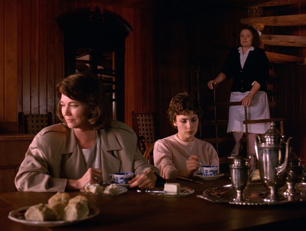 Sylvia and Audrey Horne at a dining room table with a Nurse on a staircase