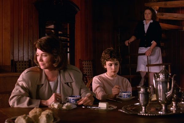 Sylvia and Audrey Horne at a dining room table with a Nurse on a staircase